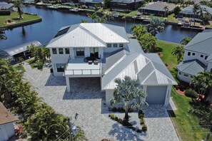 Een modern huis met twee verdiepingen, een ruime patio, een overdekte zithoek en uitzicht op een waterpartij.