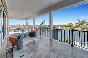 Un balcon spacieux offrant une vue sur une piscine et des palmiers.