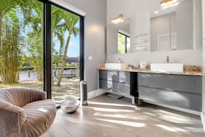 Une salle de bain moderne dotée d’une grande fenêtre, d’un double vasque et d’un miroir encastré.
