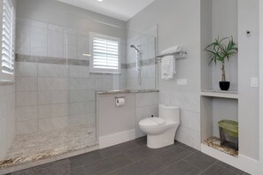 Une salle de bain moderne avec une douche, des toilettes et une plante en pot.