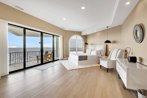 A spacious bedroom with a large sliding glass door leading to a balcony with a view of the water. - 15192 Bahia CT (Fort Myers)