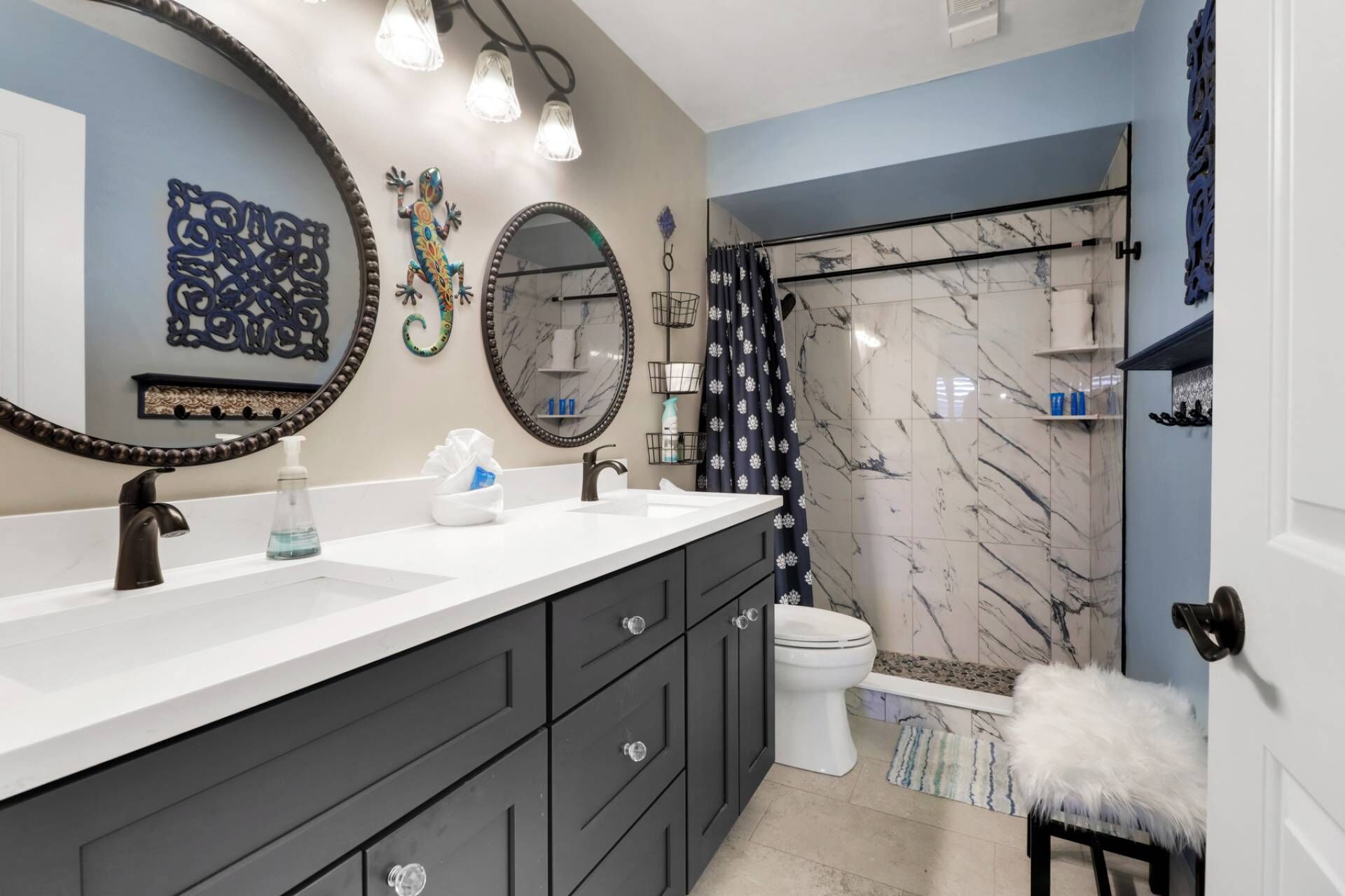 A modern bathroom with a white sink, dark cabinets, a toilet, and a shower area.