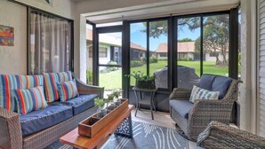 A spacious patio with wicker furniture, a wooden bench, and a view of a residential area. - 11961 Caraway Ln #87 (Fort Myers)