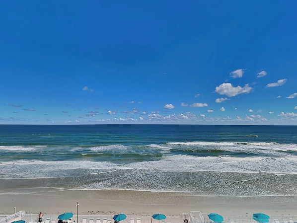 A beach with a clear sky, waves, and umbrellas. - Harbour Beach Resort 603 (Daytona Beach)