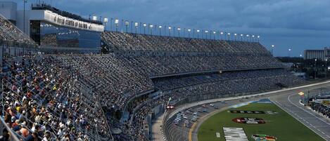 A large stadium with multiple levels of seating, a track with cars, and a Coca-Cola logo on the field.