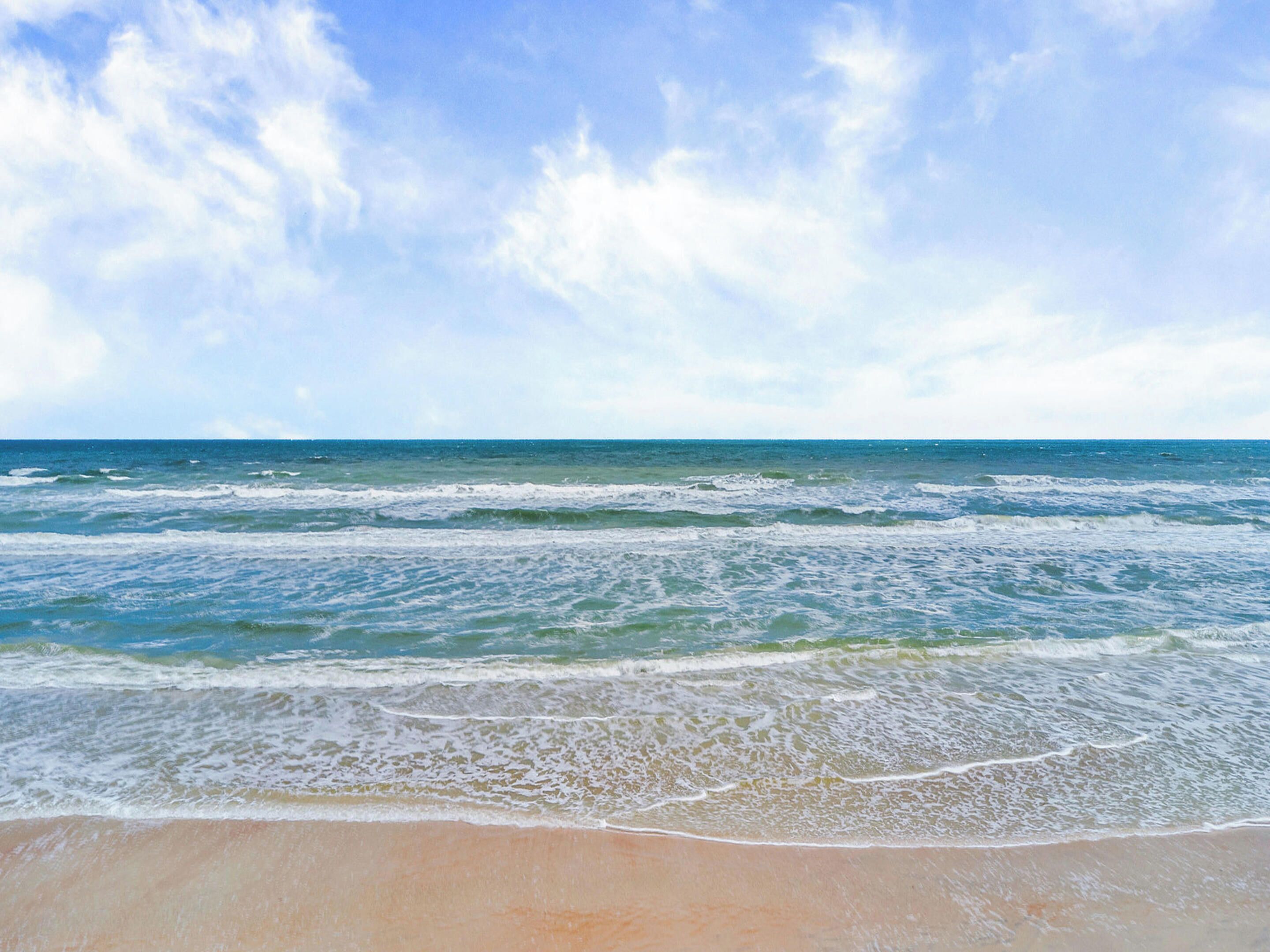 Una playa con olas y un cielo despejado.