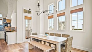 A spacious kitchen with a dining area, featuring a large wooden table, wicker chairs, and a chandelier. - Beaches and Cream 210 DEW (Port Aransas)
