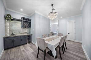 Una cocina moderna con armarios grises, salpicadero de azulejos y un comedor con mesa y sillas.