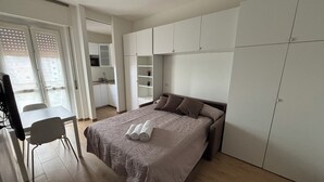 A bedroom with a bed, a desk, and a kitchenette. - Civic8-Navigli-Iulm (Milano)