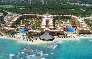 Un resort con diversi edifici, una piscina centrale e una spiaggia.
