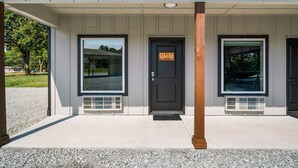 A building with three doors, each with a window above. - Affordable Lodge w/Covered, Lighted, Pull Through Parking. Grills and Outdoor TV (Grove)