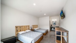 A bedroom with two beds, a small desk, and a TV. - Affordable Lodge w/Covered, Lighted, Pull Through Parking. Grills and Outdoor TV (Grove)