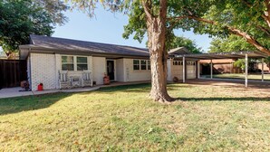 A single-story house with a covered patio and a lawn.