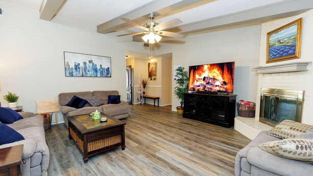 A living room with a fireplace, a television displaying a fire, and a cityscape painting on the wall.