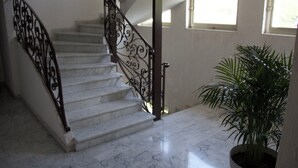 A marble staircase with ornate black metal railings leading to a landing.