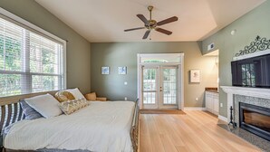 Un dormitorio con cama, ventilador de techo, chimenea y vistas al exterior a través de una puerta.
