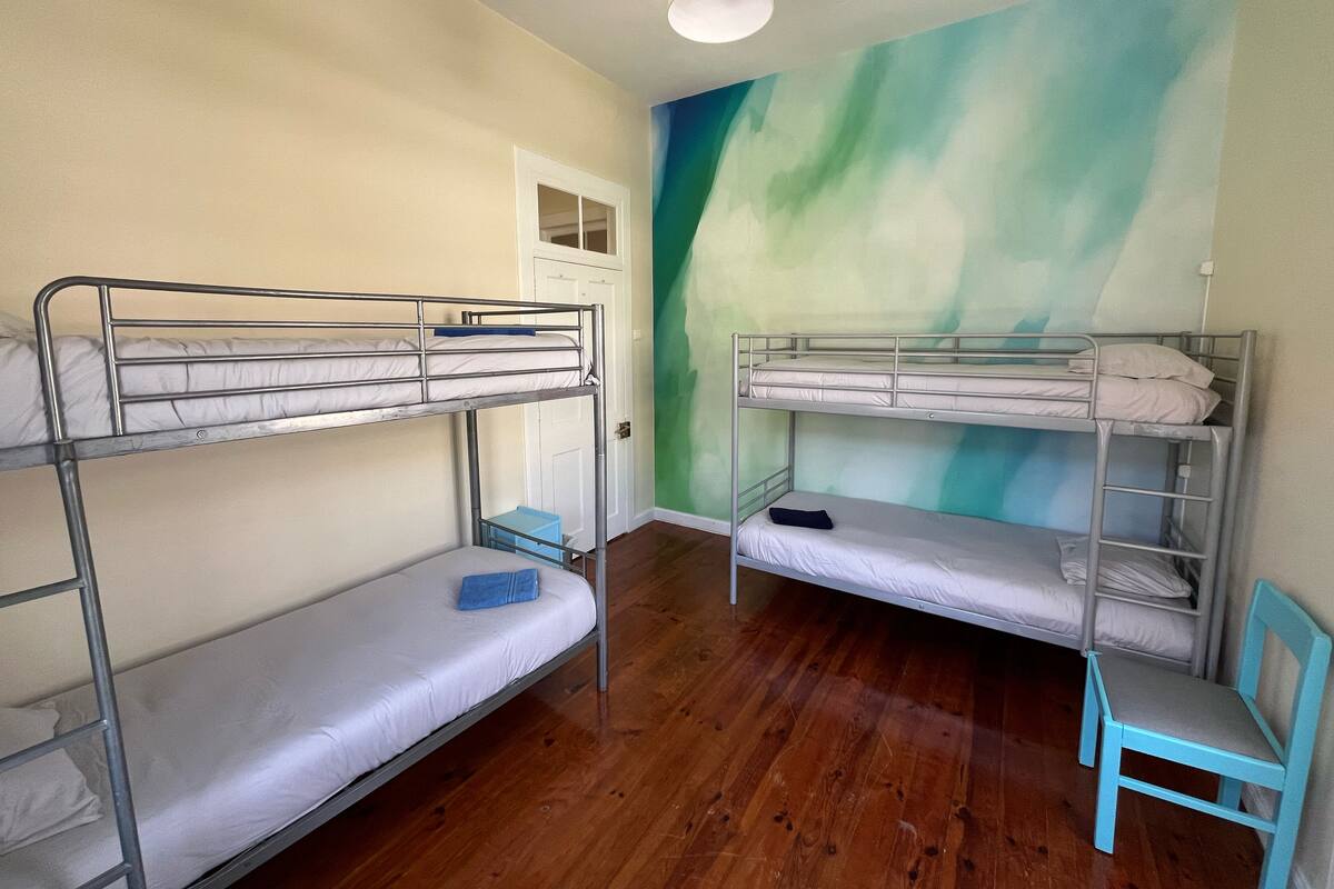 A room with two bunk beds, a small blue chair, and a door leading to another room.