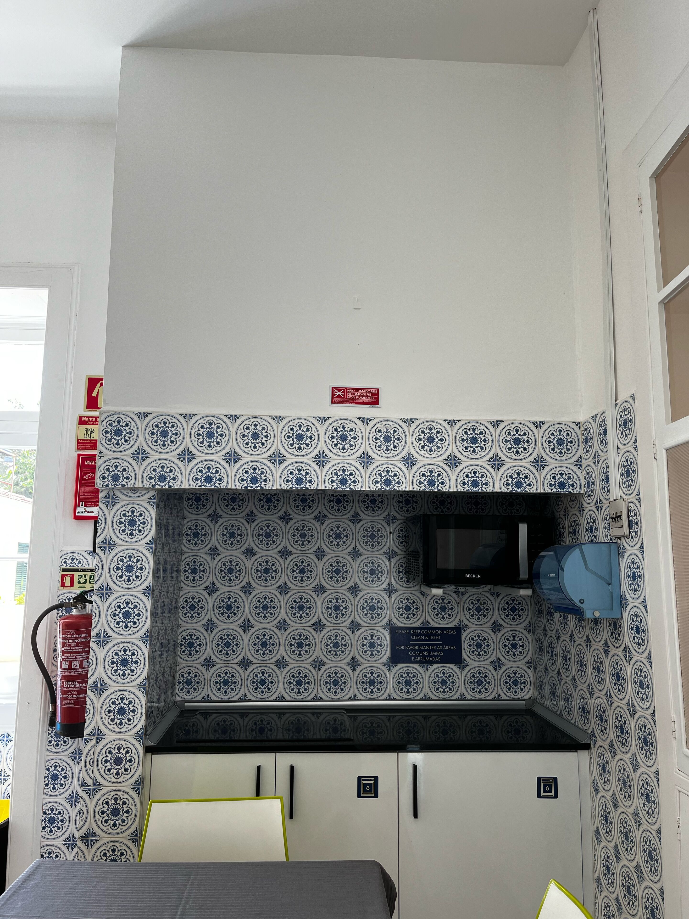 A compact kitchenette with a microwave, cabinets, and a fire extinguisher.