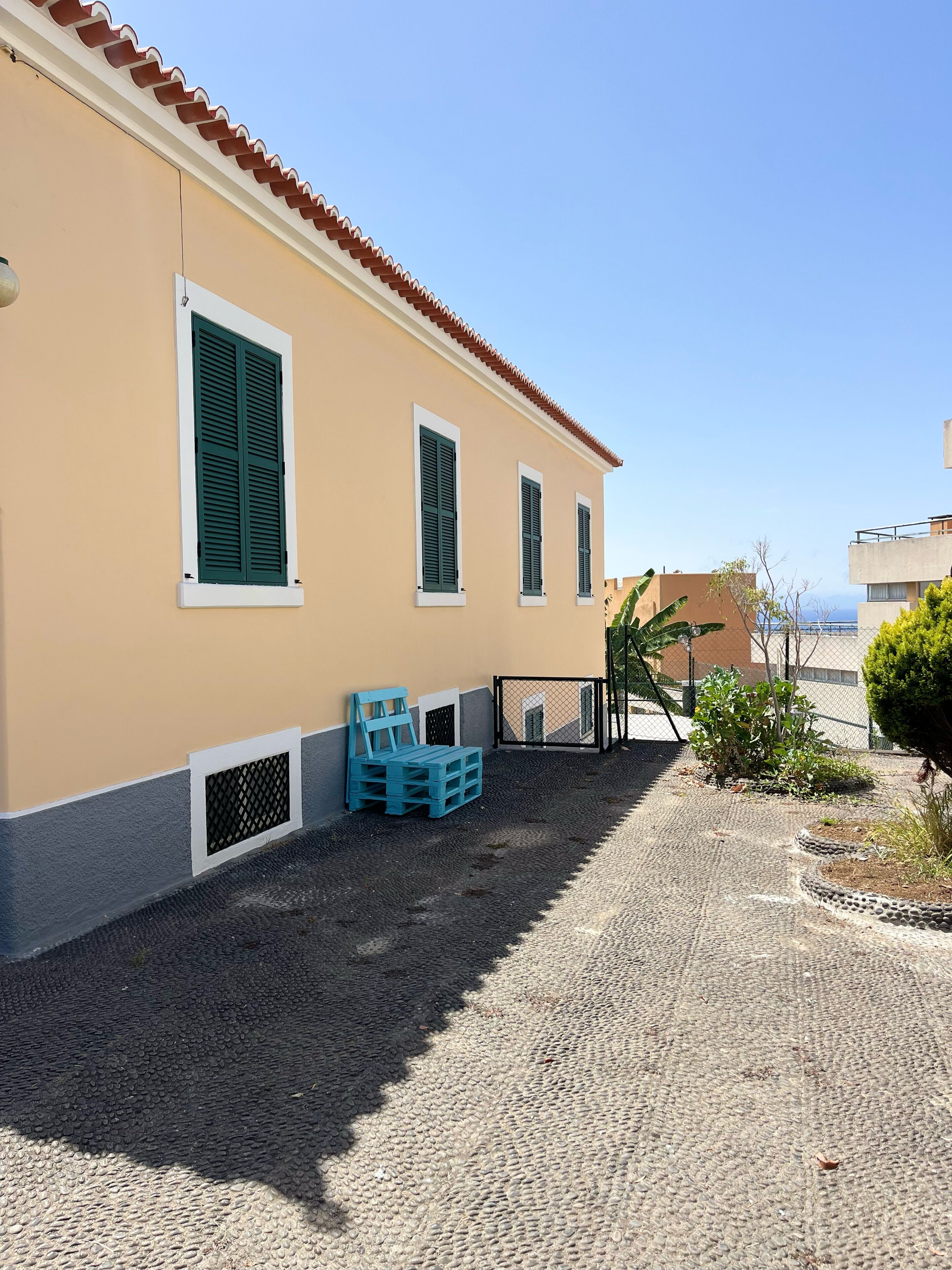 A building with three windows, a tiled roof, and a gravel driveway.