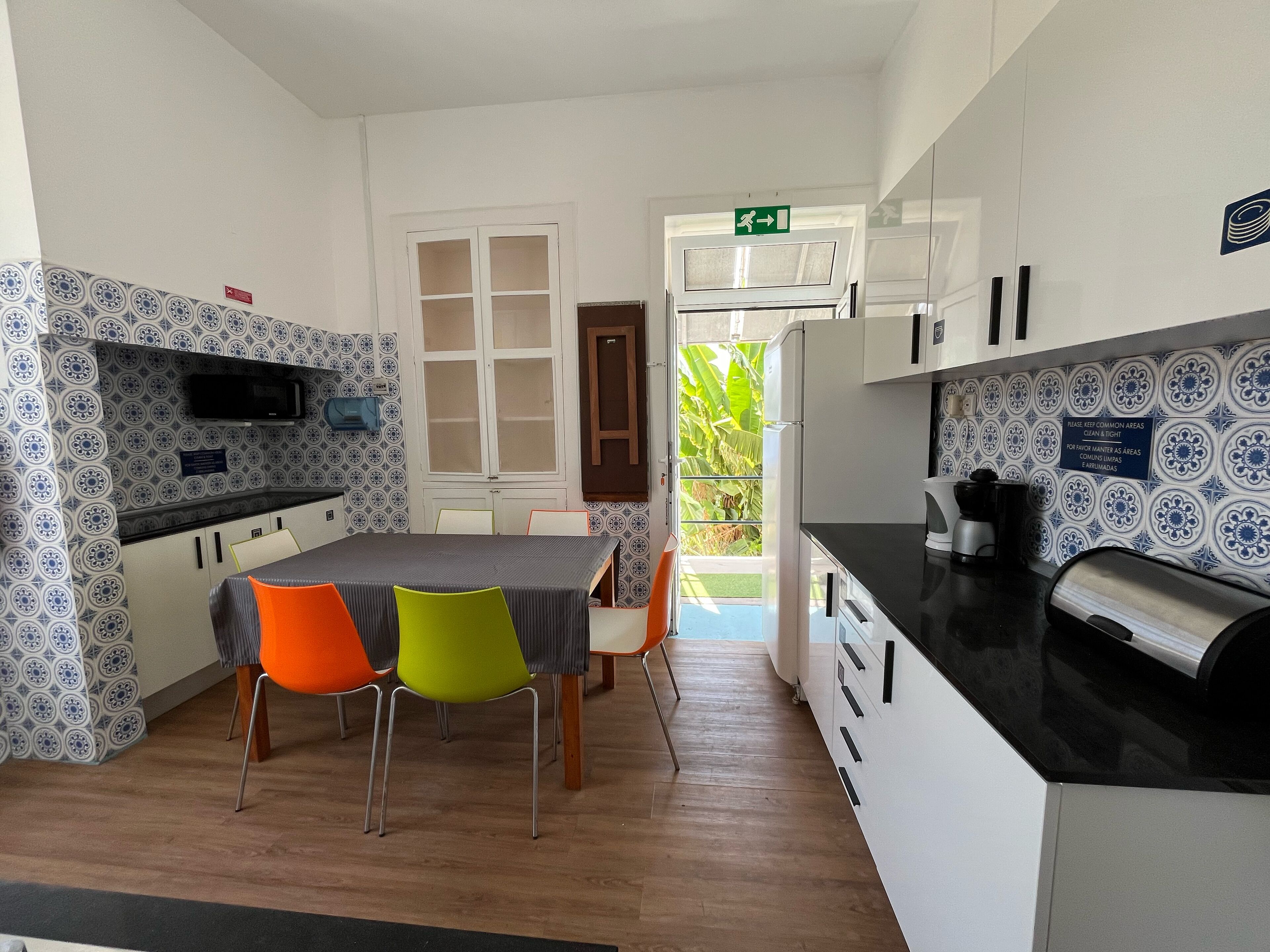 A compact kitchen with a dining area, featuring a microwave, a coffee machine, and a refrigerator.