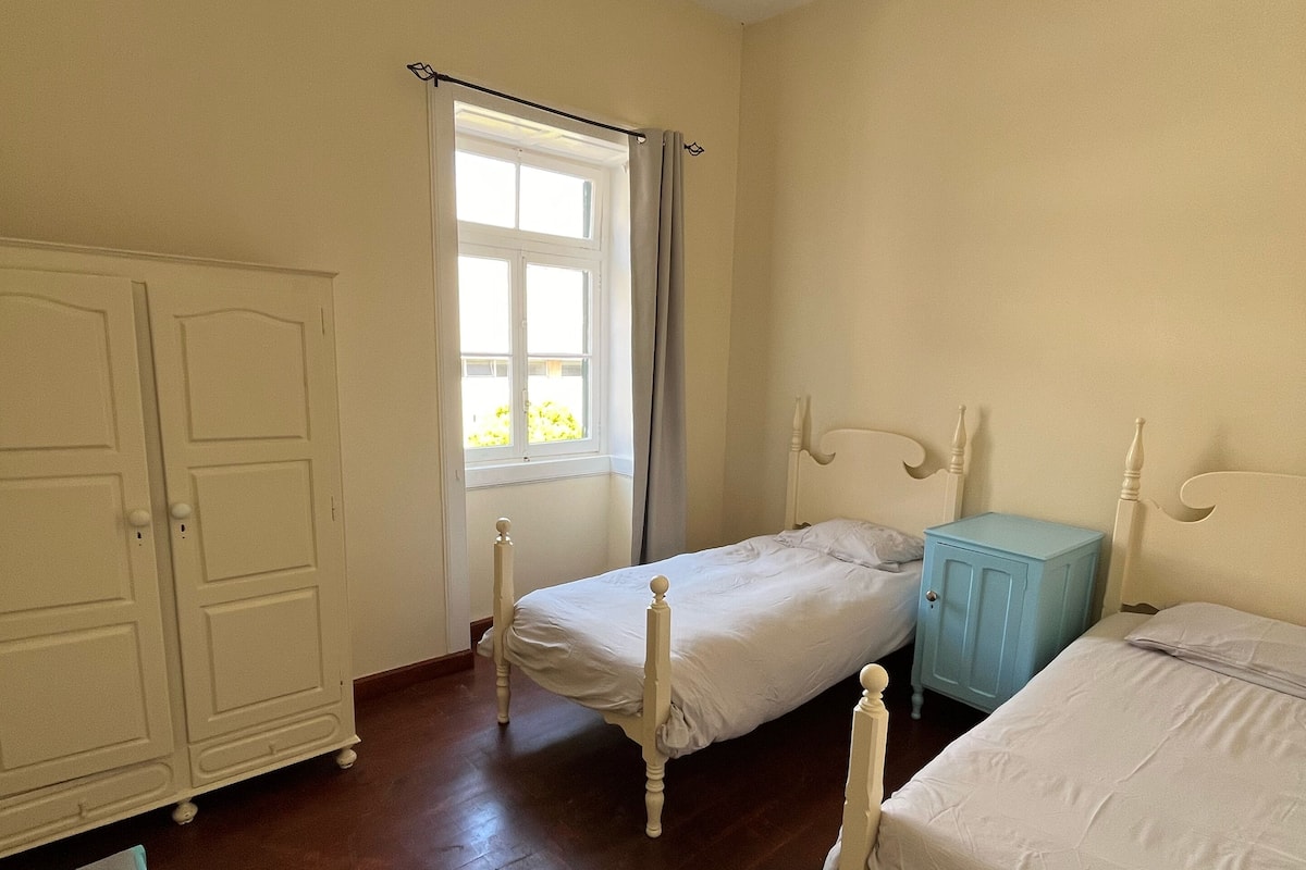 A bedroom with two single beds, a wardrobe, and a small table.