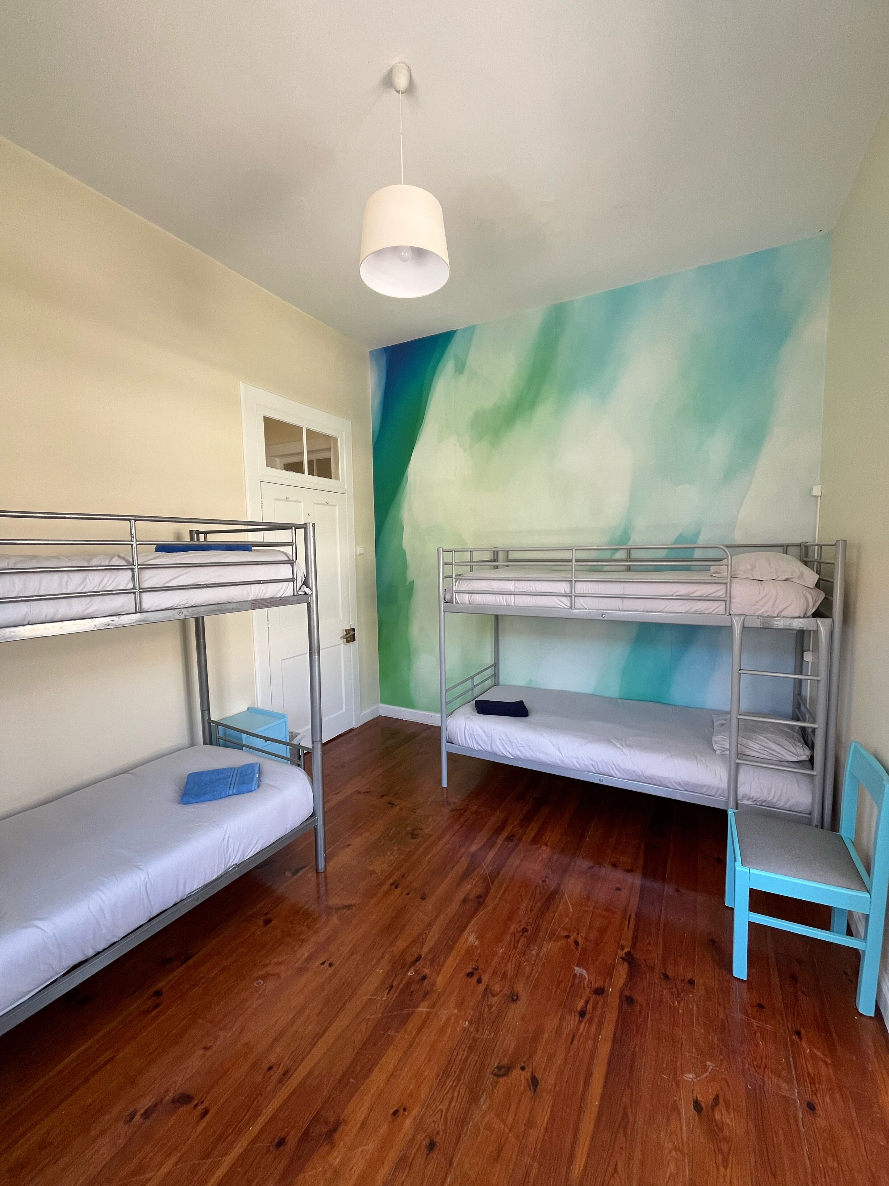 A dormitory room with bunk beds, a small desk, and a chair.