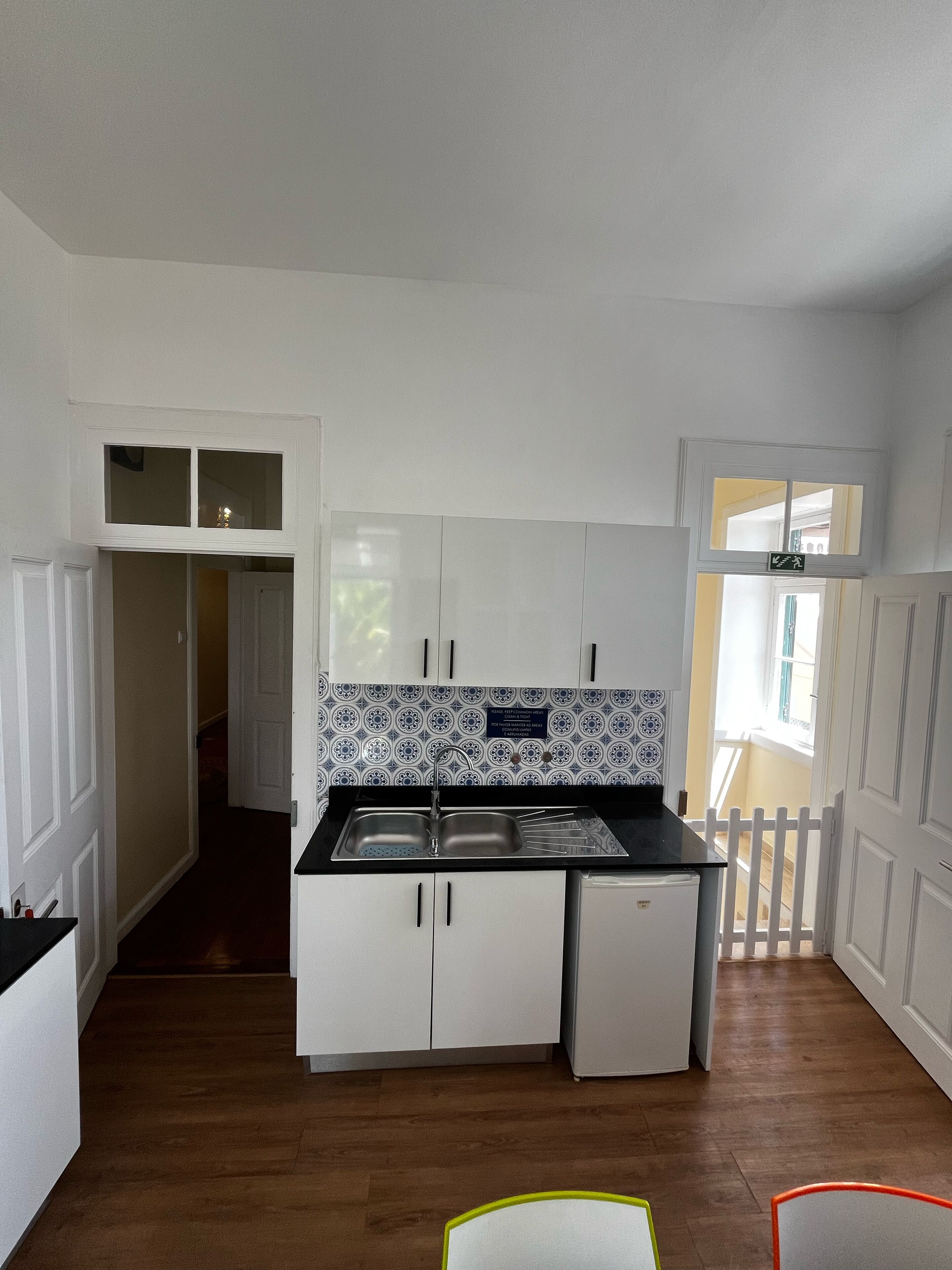 A kitchen with white cabinets, a double sink, and patterned backsplash.