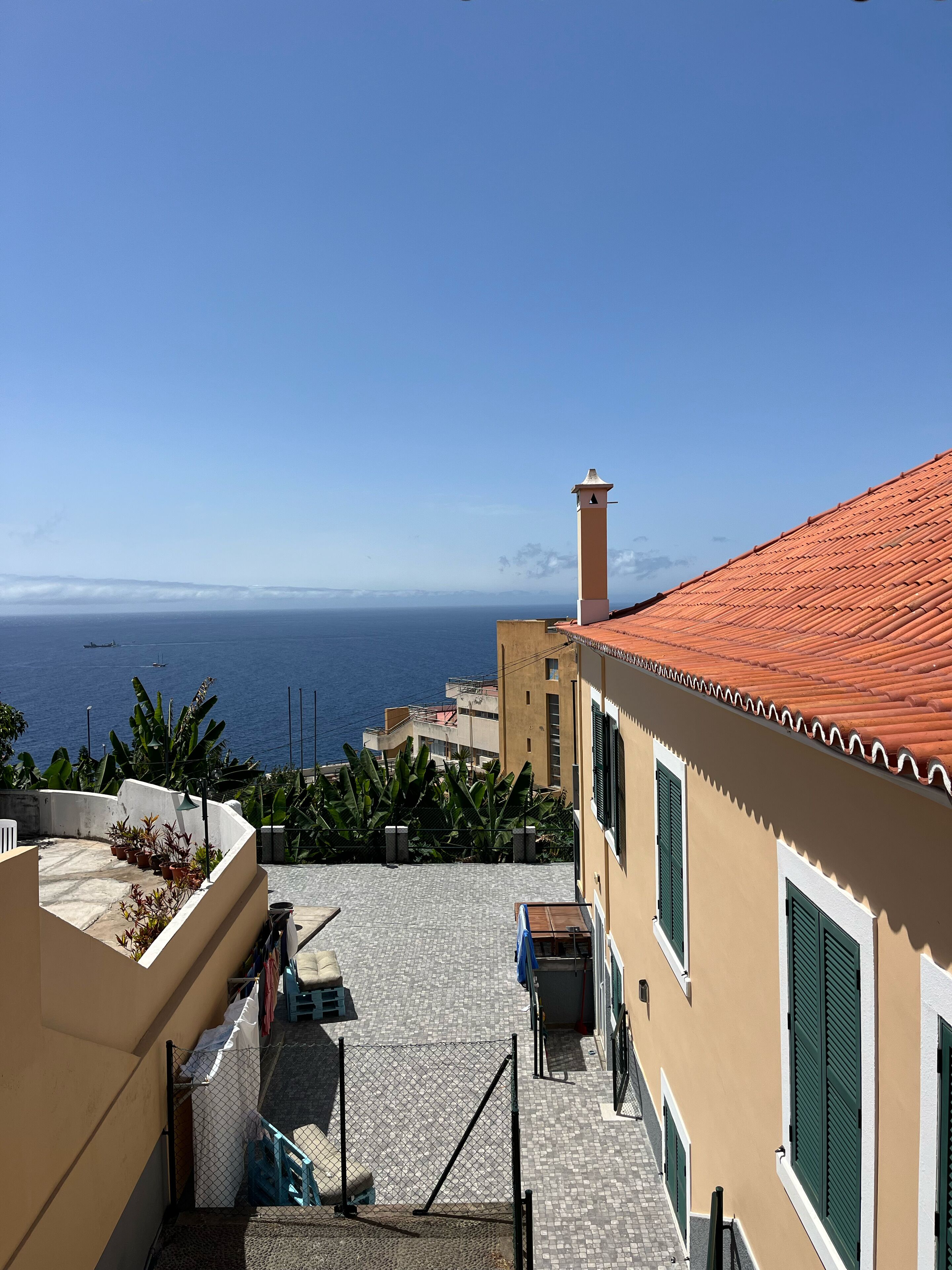 A coastal building with a tiled roof, a small tower, and a view of the sea.