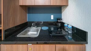 A kitchen with a stainless steel sink, a coffee maker, and two water bottles on the counter. - Studio in the heart of Morelia! (Morelia)