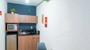 A compact kitchen with a microwave, sink, and refrigerator. There is a dining table with chairs and a small potted plant on the counter. - Studio in the heart of Morelia! (Morelia)
