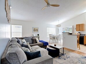 A living room with a sofa, a coffee table, and a dining area with chairs and a table.