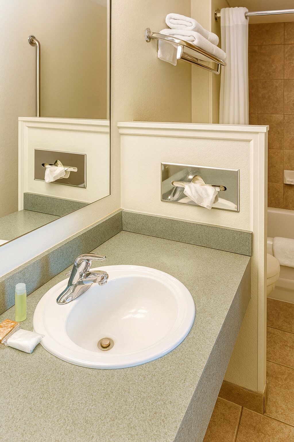 Un baño con un lavabo blanco, un espejo y barras para toallas.
