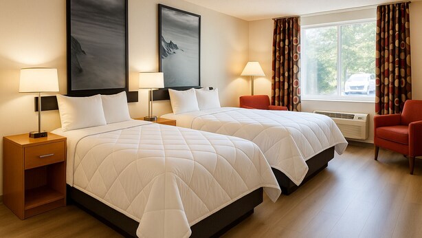 A hotel room with two beds, a nightstand, a chair, and a window with curtains. - MHO Hotel Dover (Dover)