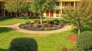 A hotel with a courtyard featuring a central circular garden, surrounded by neatly trimmed hedges and trees. - MHO Hotel Dover (Dover)