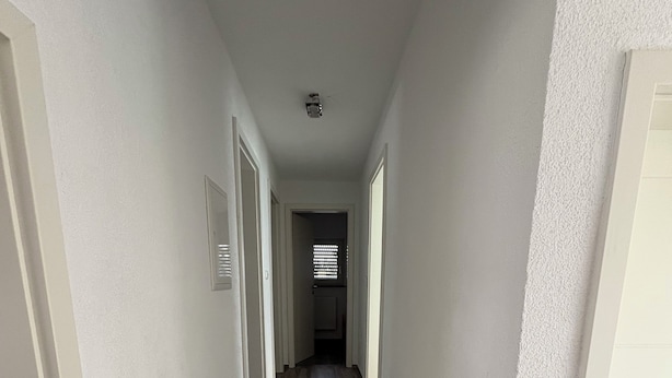 A narrow, well-lit hallway with wooden steps leading to a door at the end. - Friendly accommodation with parking in a central location (Dieburg)