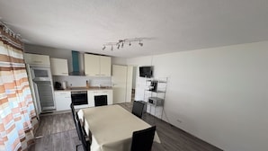 A compact kitchen with a dining table, chairs, a microwave, a stove, and a television. - Friendly accommodation with parking in a central location (Dieburg)