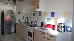 A kitchen with a stainless steel refrigerator, a microwave, a stove, and a coffee maker.