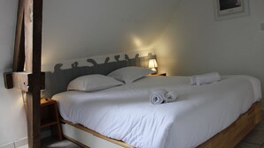 A single bed with white linens, a wooden headboard, and a nightstand with a lamp.