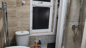 Ein Badezimmer mit Toilette, Fenster und Dusche.
