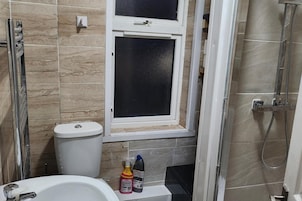 Un baño con inodoro, ventana y ducha.