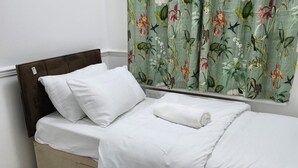 A neatly made bed with white bedding and pillows, a brown headboard, and a window with floral curtains. - Dagenham - House - Stay5 - Parking - Greatlocation (Dagenham)