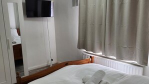 A hotel room with a bed, a television mounted on the wall, and a window with curtains. - Dagenham - House - Stay5 - Parking - Greatlocation (Dagenham)