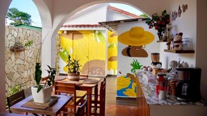 A dining area with a stone wall, wooden furniture, and a colorful mural. - HOTEL MONTESILVA (Puerto Plata)