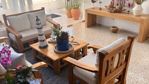A modern living room with a sofa, coffee table, and chairs, featuring a decorative lighthouse, potted plants, and a painting on the wall. - HOTEL MONTESILVA (Puerto Plata)