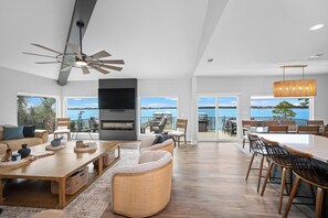 A spacious living area with a fireplace, seating, and large windows offering a view of the outdoors.