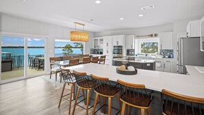 A modern kitchen with a large island, white cabinetry, and a view of the sea. - Luxury Waterfront Villa w/ Pool, Hot Tub, Dock & Game Room - Sleeps 28 (Pensacola)