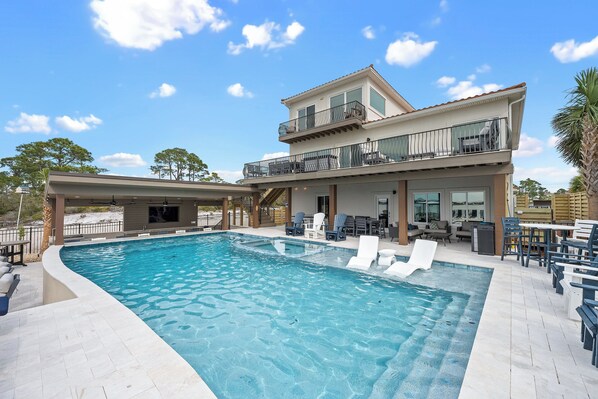 A two-story building with a swimming pool, outdoor seating, and a covered patio area.