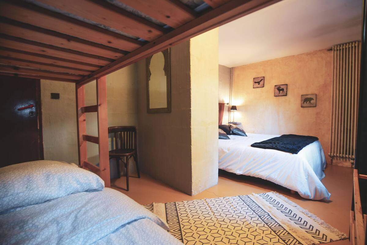 A bedroom with a bed, a chair, a mirror, and a patterned rug.