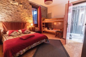 A bedroom with a bunk bed, a wooden headboard, a nightstand, a lamp, and a view of a mountain through a window. - Gîte l'Aurienchon (Auris)