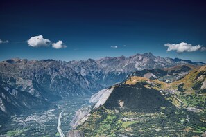 A mountainous landscape with a valley, a winding road, and a small settlement. - Gîte l'Aurienchon (Auris)